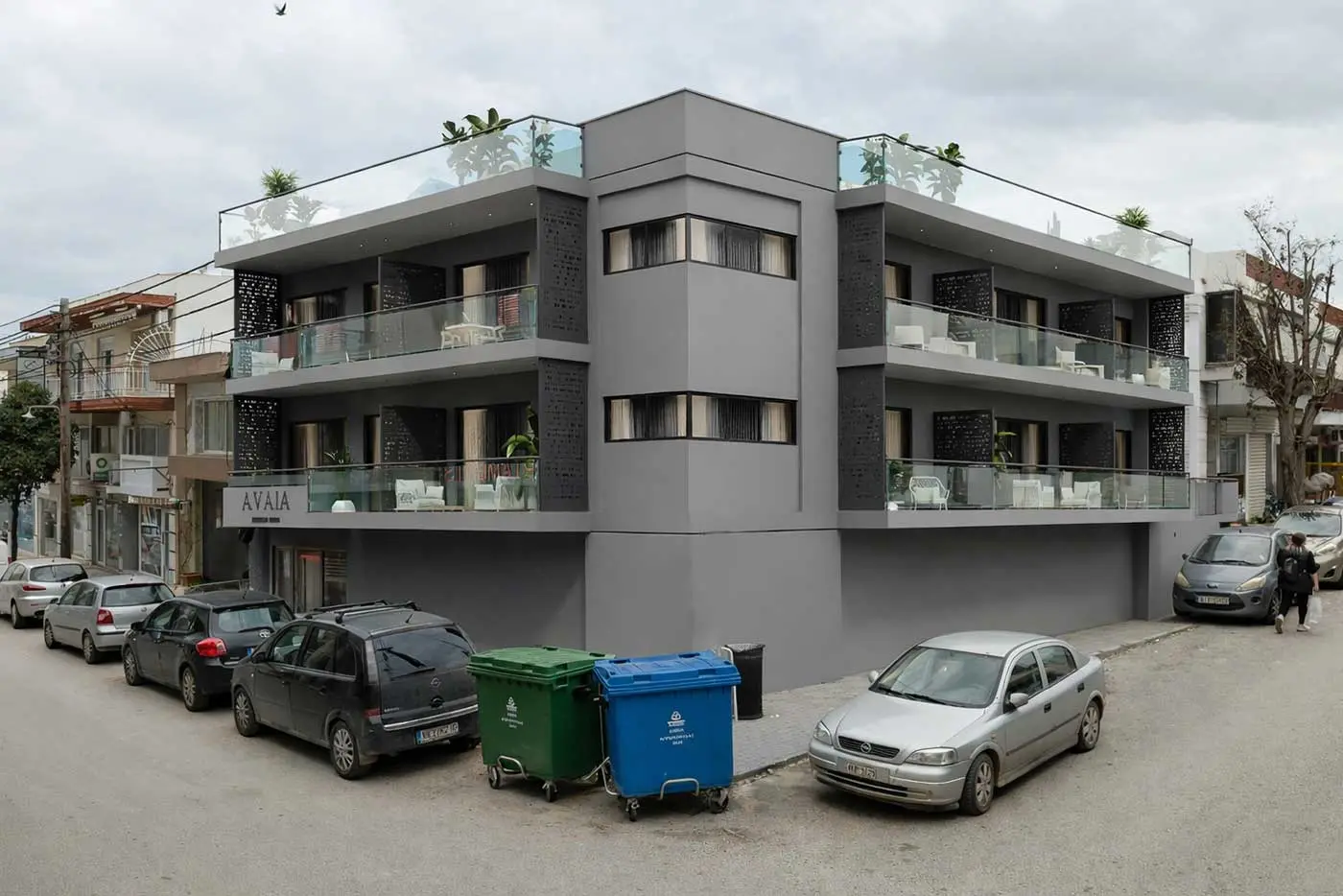 Exterior of AVAIA a modern three-story boutique hotel building with glass balconies and minimalist architecture in an urban seaside setting.