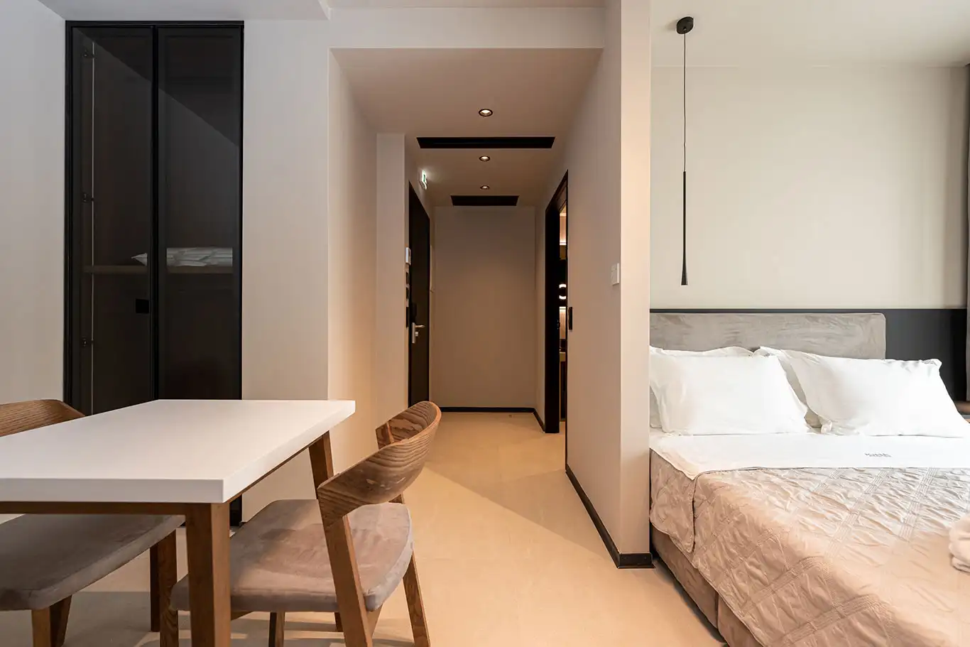 Wide interior of Accessible Grand Luxury Room 107 with double bed, dining table, chairs, wardrobe and entrance hallway