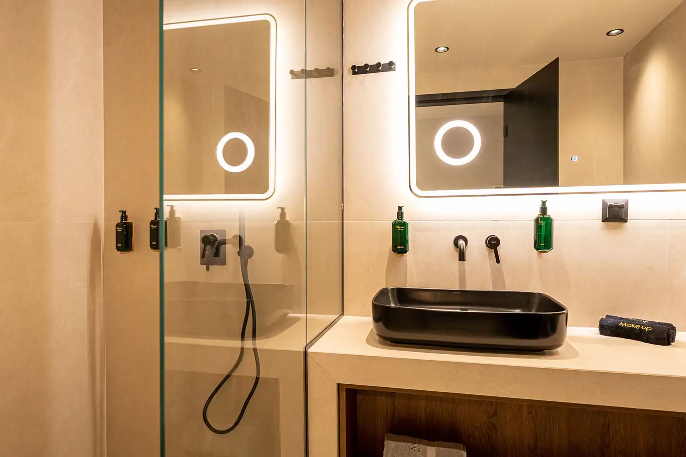Bathroom with black rectangular basin, illuminated mirror and glass shower with matte black fixtures