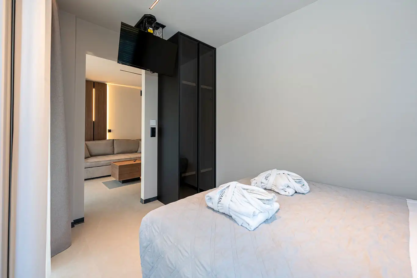 Bedroom with double bed, bathrobes, wall-mounted TV and access to the living area