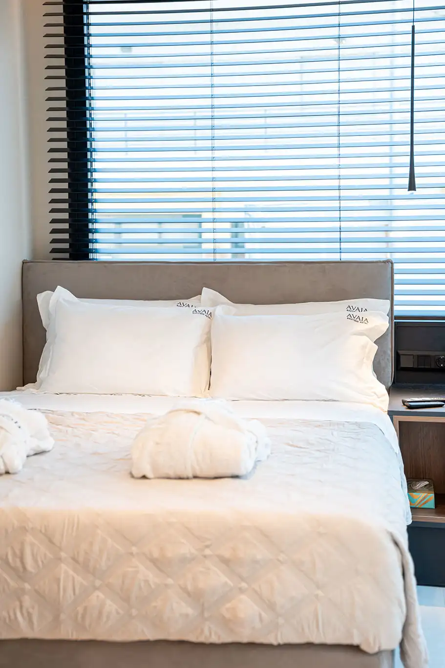Front detail of a double bed with white pillows, premium bedding and folded bathrobes