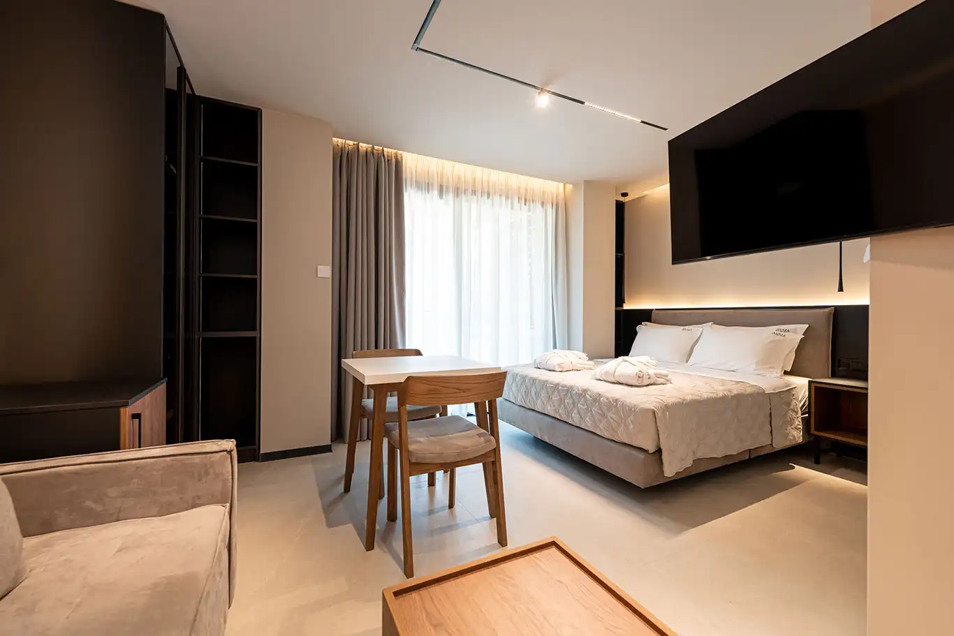 Ευρεία λήψη στο Superior Luxury δωμάτιο 103 με διπλό κρεβάτι, τραπέζι φαγητού, καναπέ, τηλεόραση και μεγάλο παράθυρο