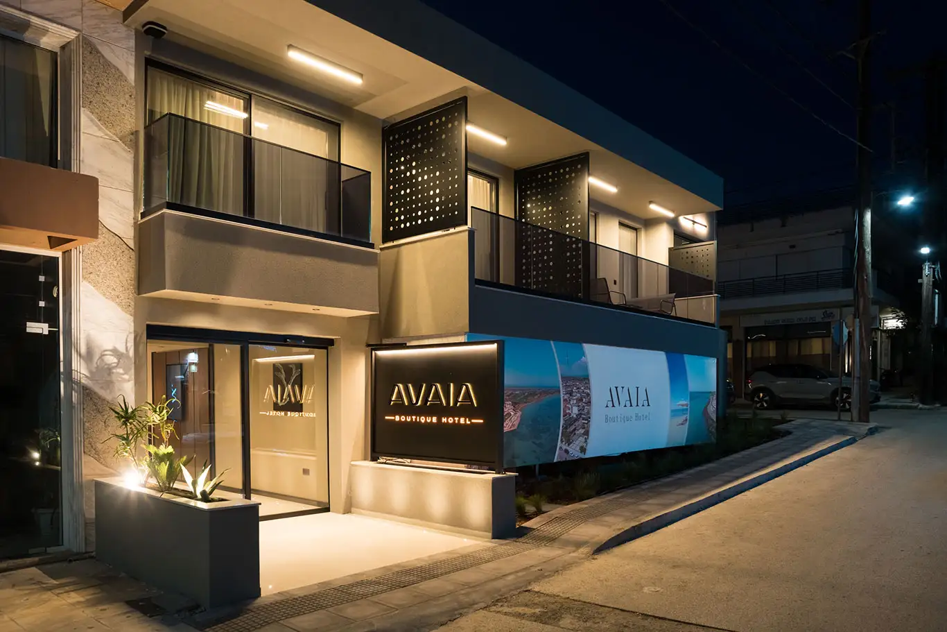 Angled night view of Avaia Boutique Hotel in Moudania with illuminated entrance and balconies