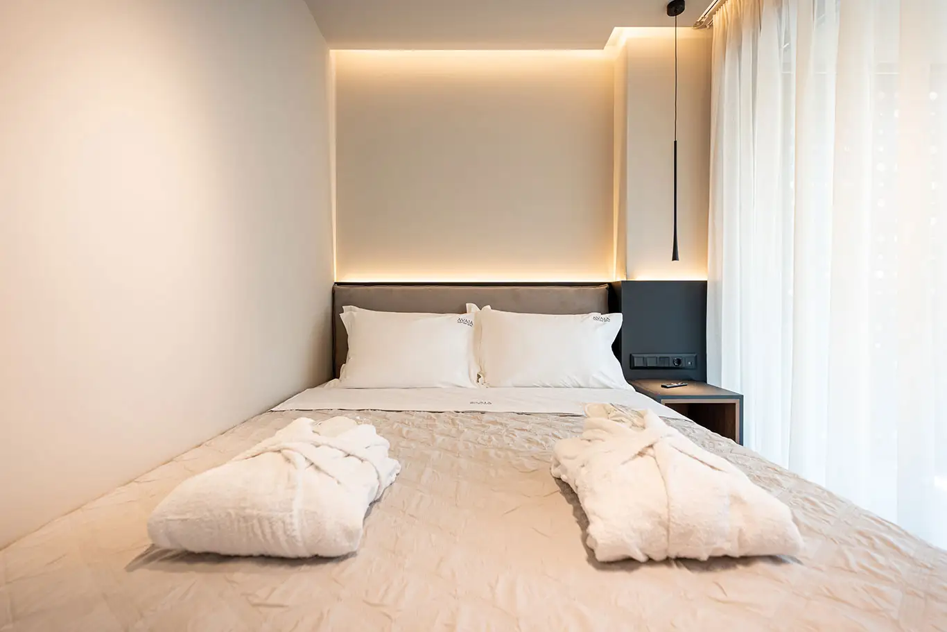 Modern double bed with two bathrobes and natural light in Classic Luxury Room 101