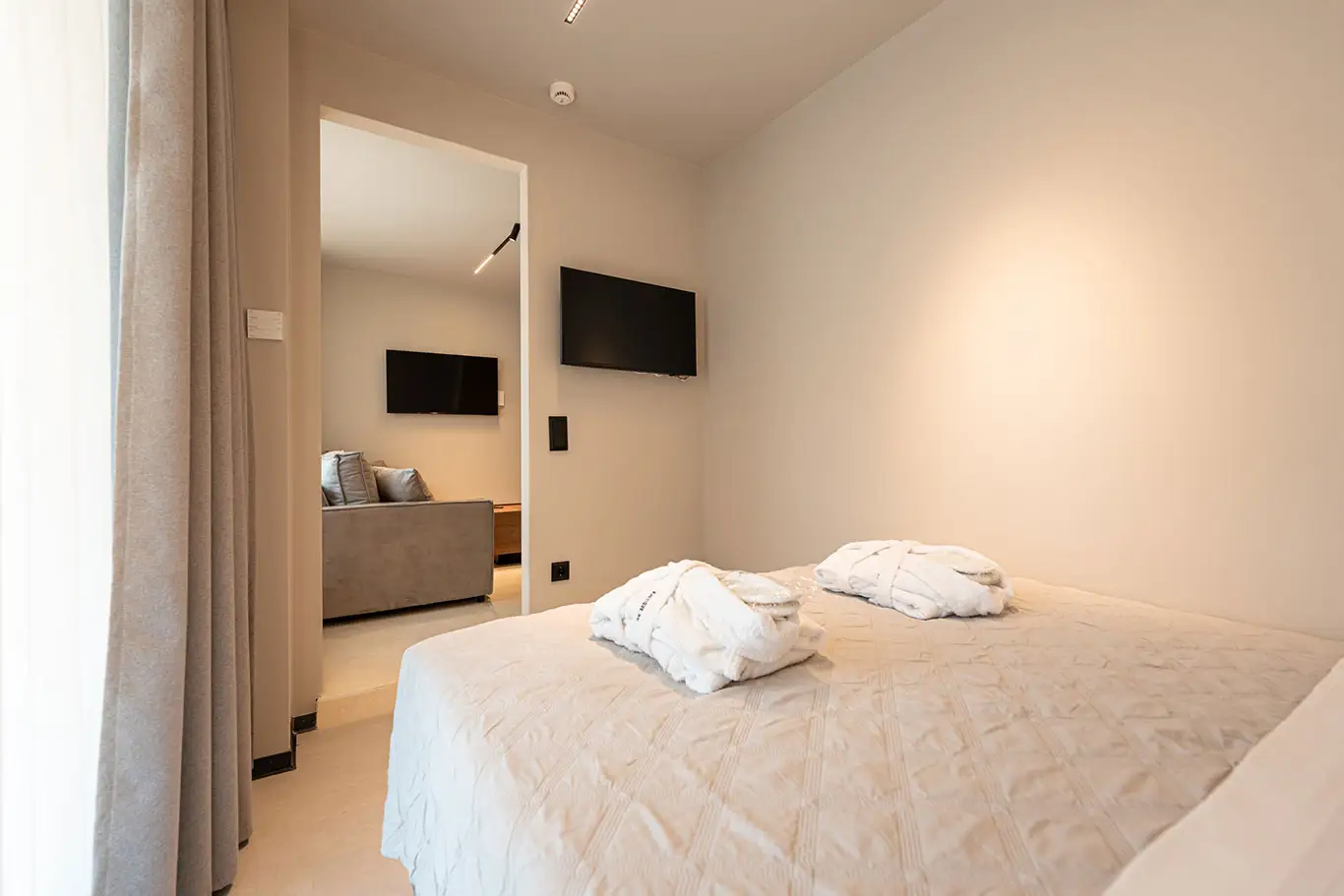 Double bedroom with bathrobes, wall-mounted TV and access to the living area in Classic Luxury Room 101