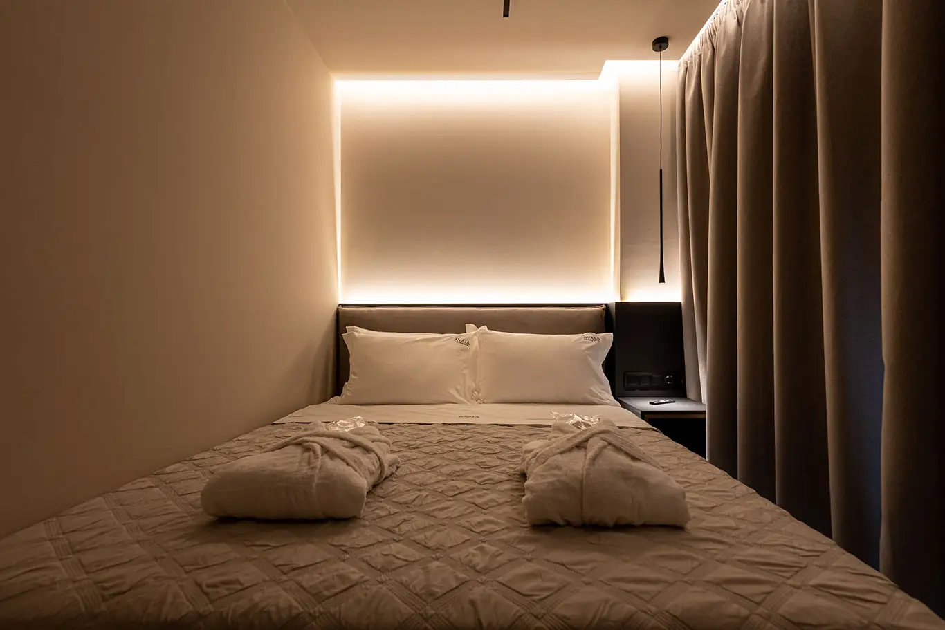 Front view of the double bed with folded bathrobes and ambient lighting in Classic Luxury Room 101