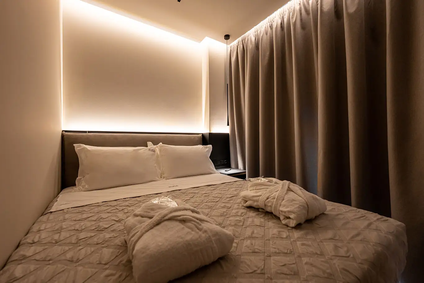 Double bed with bathrobes and warm ambient lighting in Classic Luxury Room 101 at Avaia Boutique Hotel